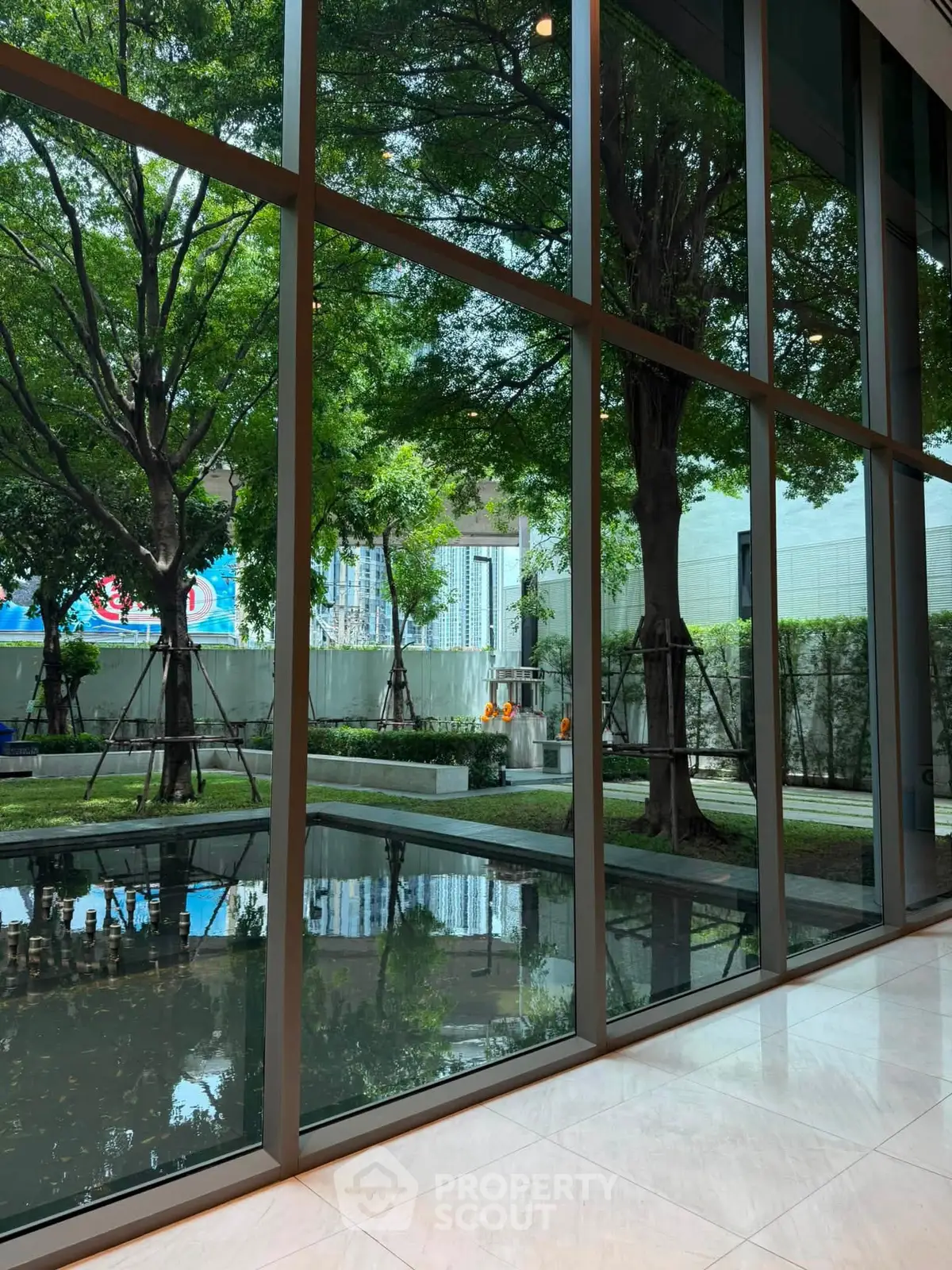 Luxurious building lobby with floor-to-ceiling windows overlooking a serene garden view.