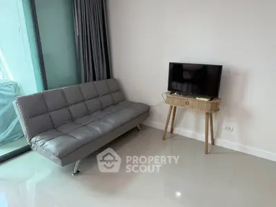 Modern living room with sleek gray sofa and flat-screen TV on stylish wooden stand.