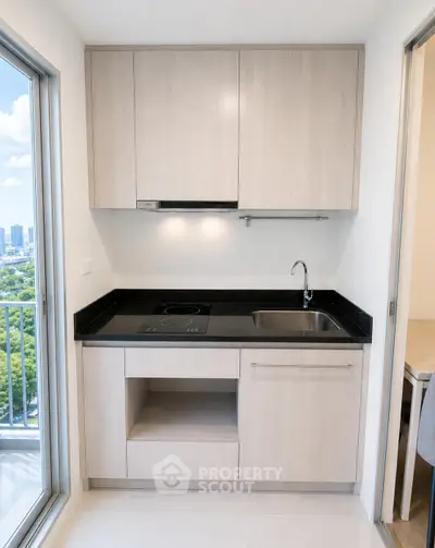 Modern kitchen with sleek cabinetry and balcony view in a high-rise apartment.