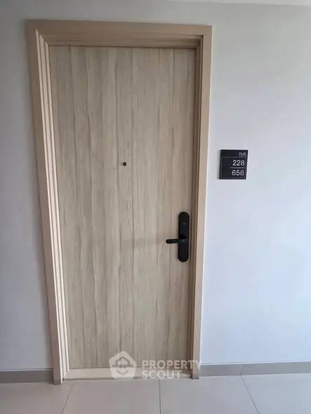 Modern apartment entrance with sleek wooden door and room number plaque.