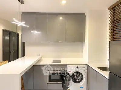 Modern kitchen with sleek cabinets, built-in appliances, and washing machine in stylish apartment.