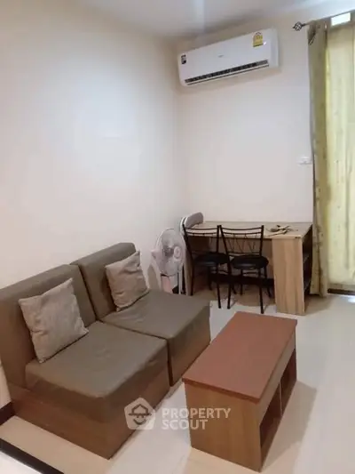 Cozy living room with modern sofa, air conditioning, and study desk, perfect for relaxation and work.