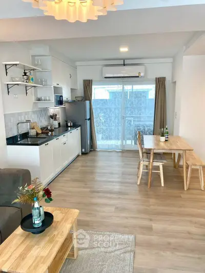 Modern open-plan living room and kitchen with wooden flooring and stylish decor.