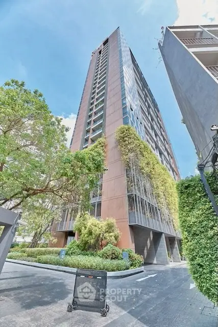 Modern high-rise building with lush greenery and clear blue sky