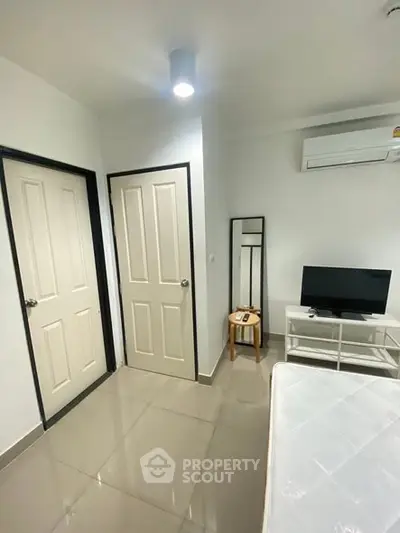 Modern bedroom with sleek design, featuring a TV, air conditioning, and minimalist decor.