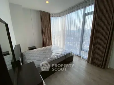 Modern bedroom with large windows and city view, featuring sleek furniture and natural light.