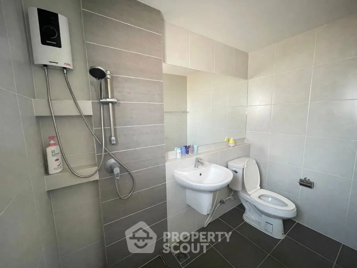 Modern bathroom with sleek tiles and shower unit, featuring a clean and minimalist design.