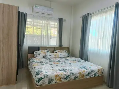 Bright and cozy bedroom with floral bedding and ample natural light from large windows.