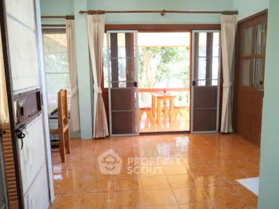 Charming living room with sliding doors opening to a sunny balcony, featuring elegant tile flooring.