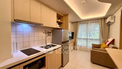 Modern kitchen with sleek cabinetry and cozy living area in open layout apartment.