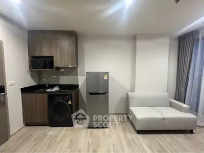 Modern apartment interior with compact kitchen and cozy living area, featuring sleek appliances and stylish decor.