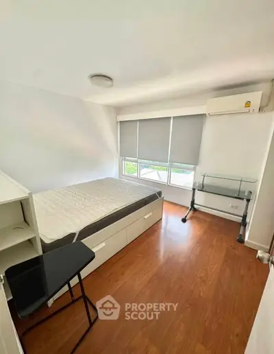 Modern bedroom with wooden flooring, large window, and minimalist furniture.