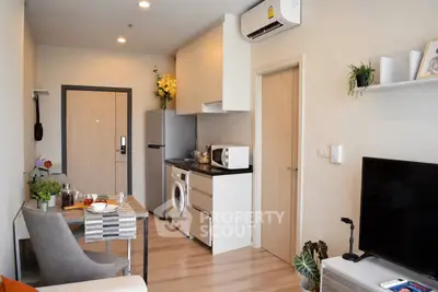 Modern apartment interior with open kitchen and cozy living area, featuring stylish decor and natural light.