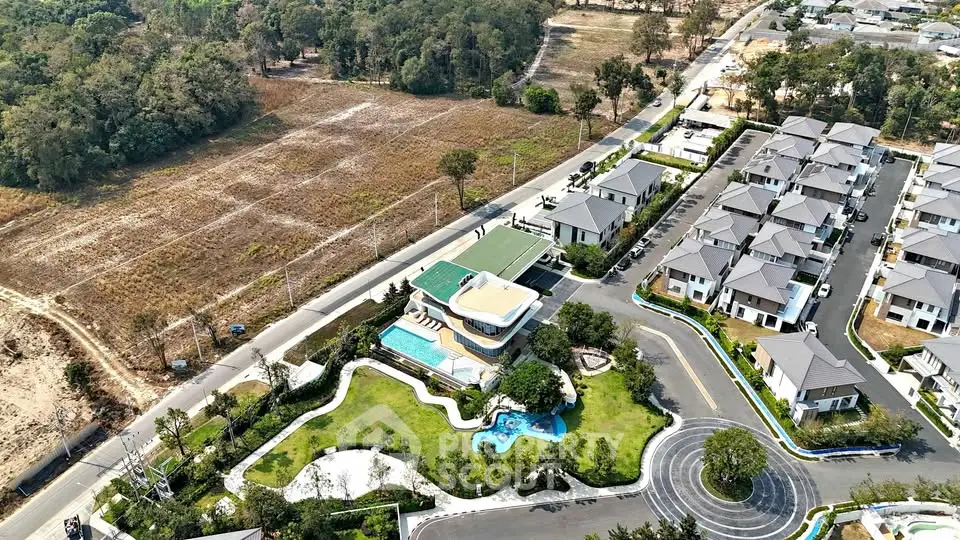 Aerial view of modern residential community with landscaped gardens and pool.