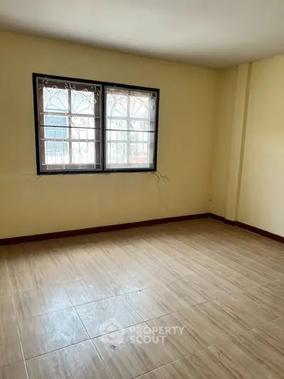 Spacious empty room with tiled flooring and large windows, perfect for customization.
