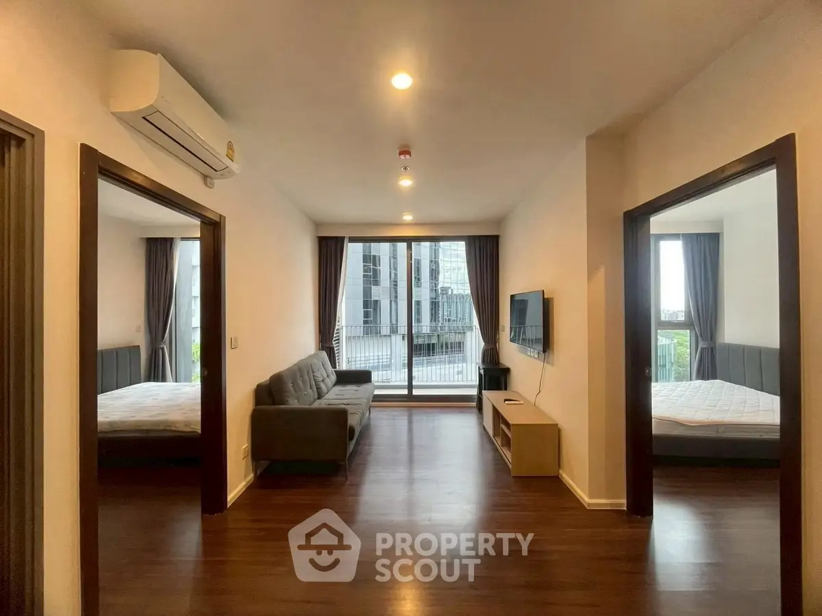 Spacious modern living room with two bedrooms and large windows offering city views.