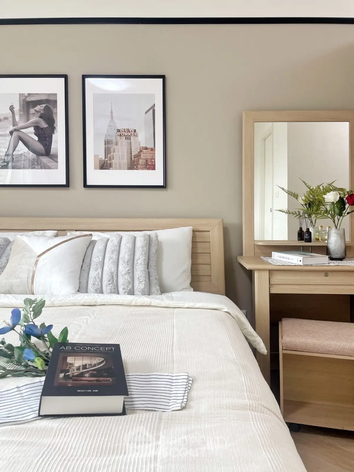 Elegant bedroom with stylish decor and cozy bedding, featuring a wooden vanity and framed art.