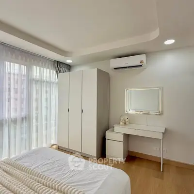 Modern bedroom with natural light, sleek furniture, and air conditioning.