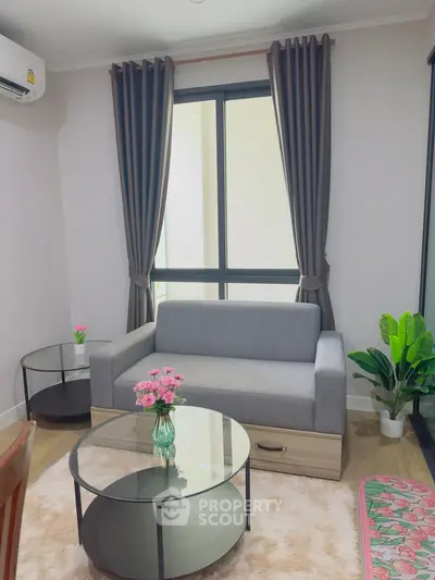 Cozy living room with modern gray sofa, glass coffee table, and elegant curtains.