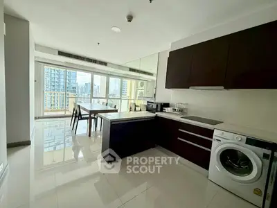 Modern open-layout kitchen with sleek appliances and city view from large windows.