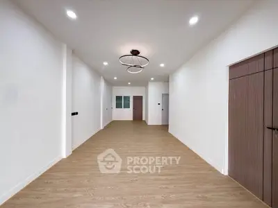 Spacious empty room with modern lighting and wooden flooring, ideal for customization.