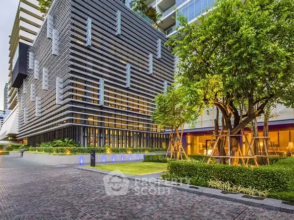Modern architectural building exterior with lush landscaping and paved entrance.