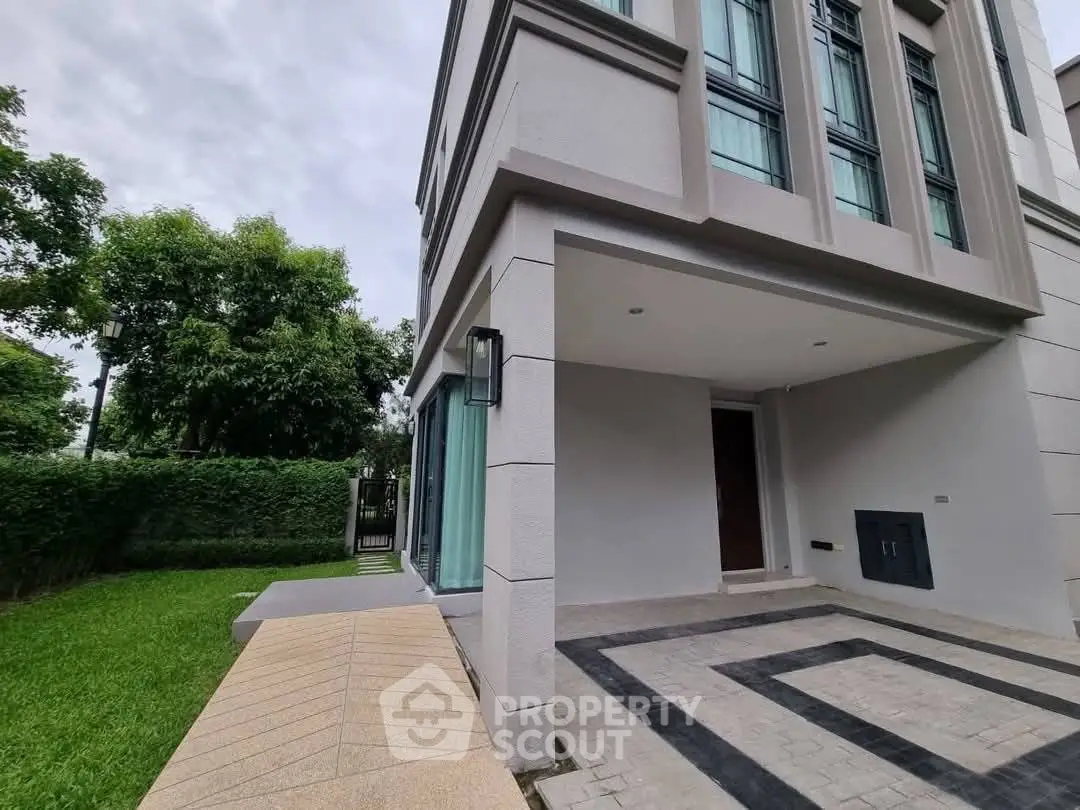 Modern townhouse exterior with lush green garden and stylish entrance.