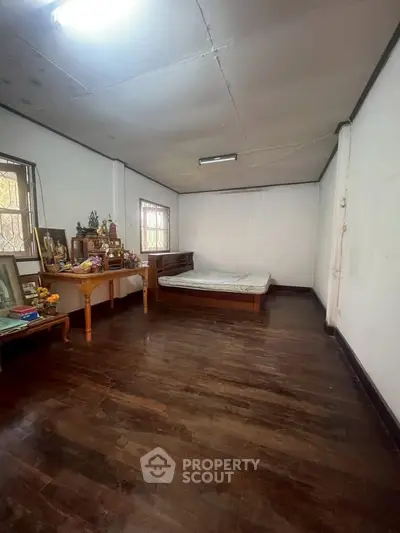 Spacious bedroom with wooden flooring and natural light, ideal for cozy living.