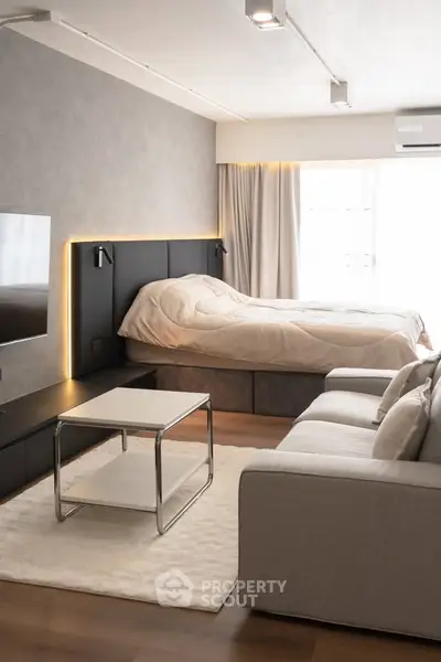 Modern living room with cozy sofa, stylish coffee table, and elegant bed in a bright, airy space.