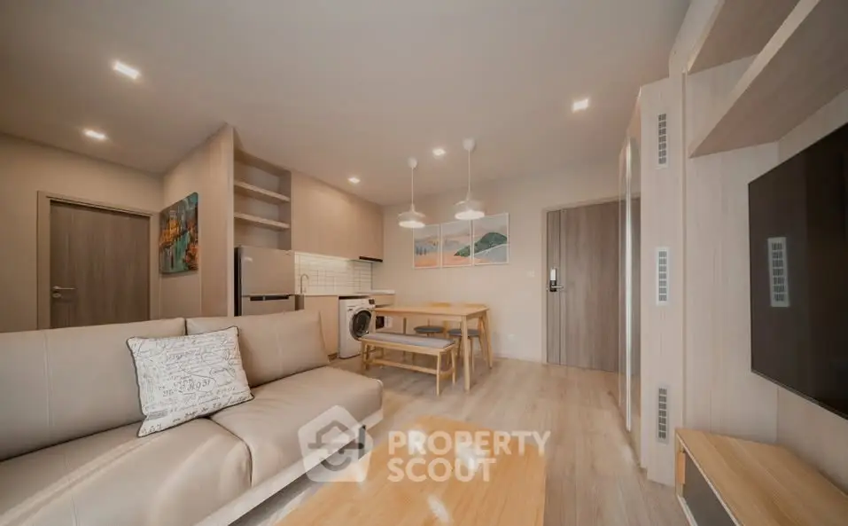 Modern open-plan living room with kitchen, featuring stylish decor and cozy seating area.