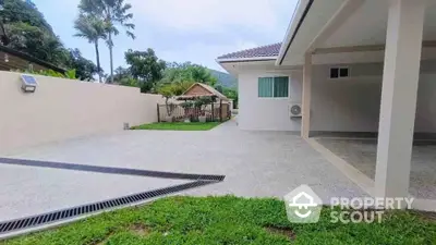 Spacious modern driveway with lush greenery and covered parking area