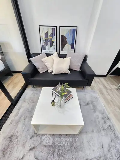 Modern living room with stylish black sofa, cozy cushions, and elegant decor on a plush rug.