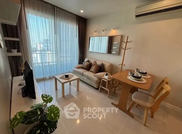 Modern living room with cozy seating and dining area, featuring large windows and air conditioning.