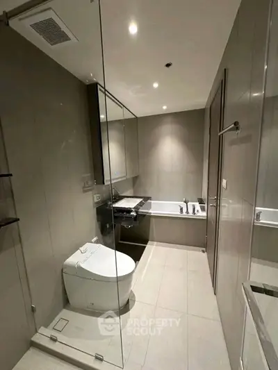 Modern bathroom with glass shower and bathtub in luxury apartment.