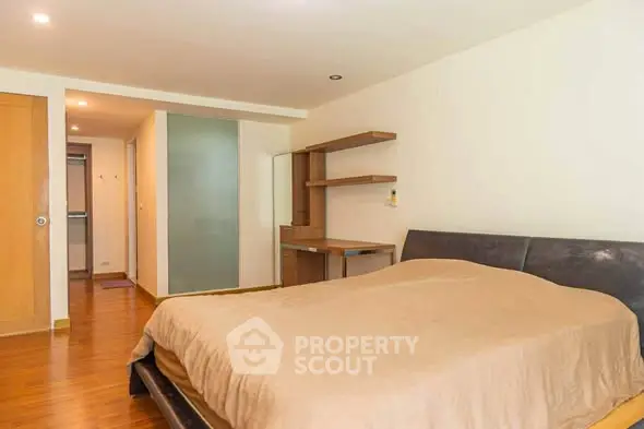 Spacious bedroom with modern furnishings and wooden flooring in a cozy apartment.