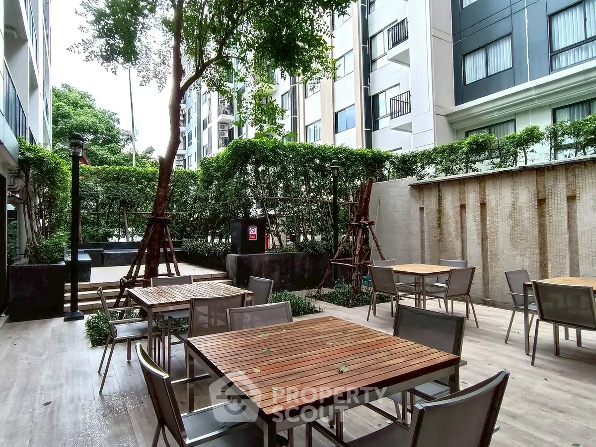 Chic outdoor seating area in modern apartment complex with lush greenery and stylish furniture.