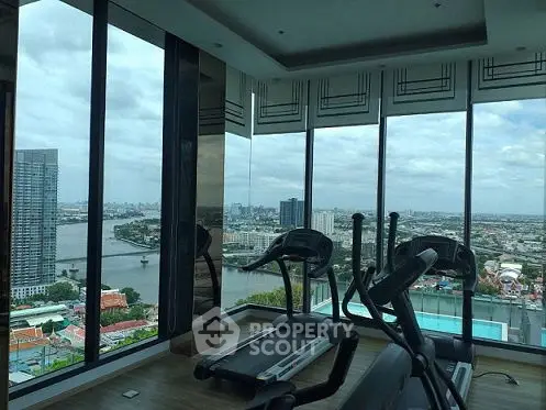 Luxurious high-rise gym with panoramic city and river views, featuring modern exercise equipment.