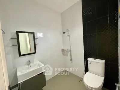Modern bathroom with sleek black and white design, featuring a shower and stylish vanity.