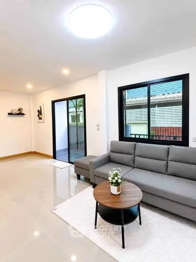 Modern living room with sleek gray sofa, stylish coffee table, and large windows offering natural light.