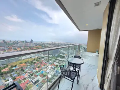 Stunning high-rise balcony with panoramic city and ocean views, featuring elegant outdoor seating and a luxurious bathtub.