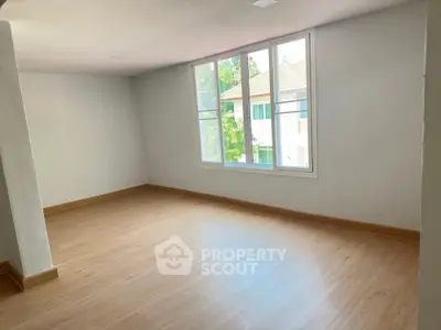Spacious and well-lit empty room with large windows offering a serene tree-lined view, perfect canvas for personalized interior design.
