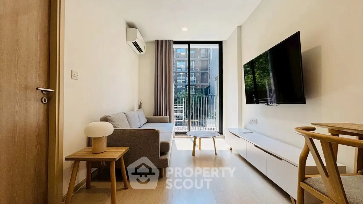 Modern living room with sleek furniture and large window offering natural light and city view.