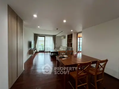 Spacious living room with wooden flooring and modern furniture in a bright apartment.
