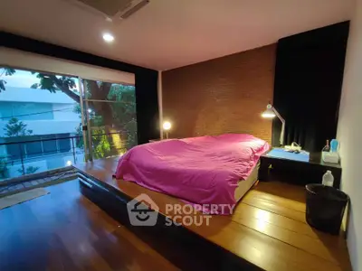 Spacious bedroom with modern design and large window overlooking greenery.