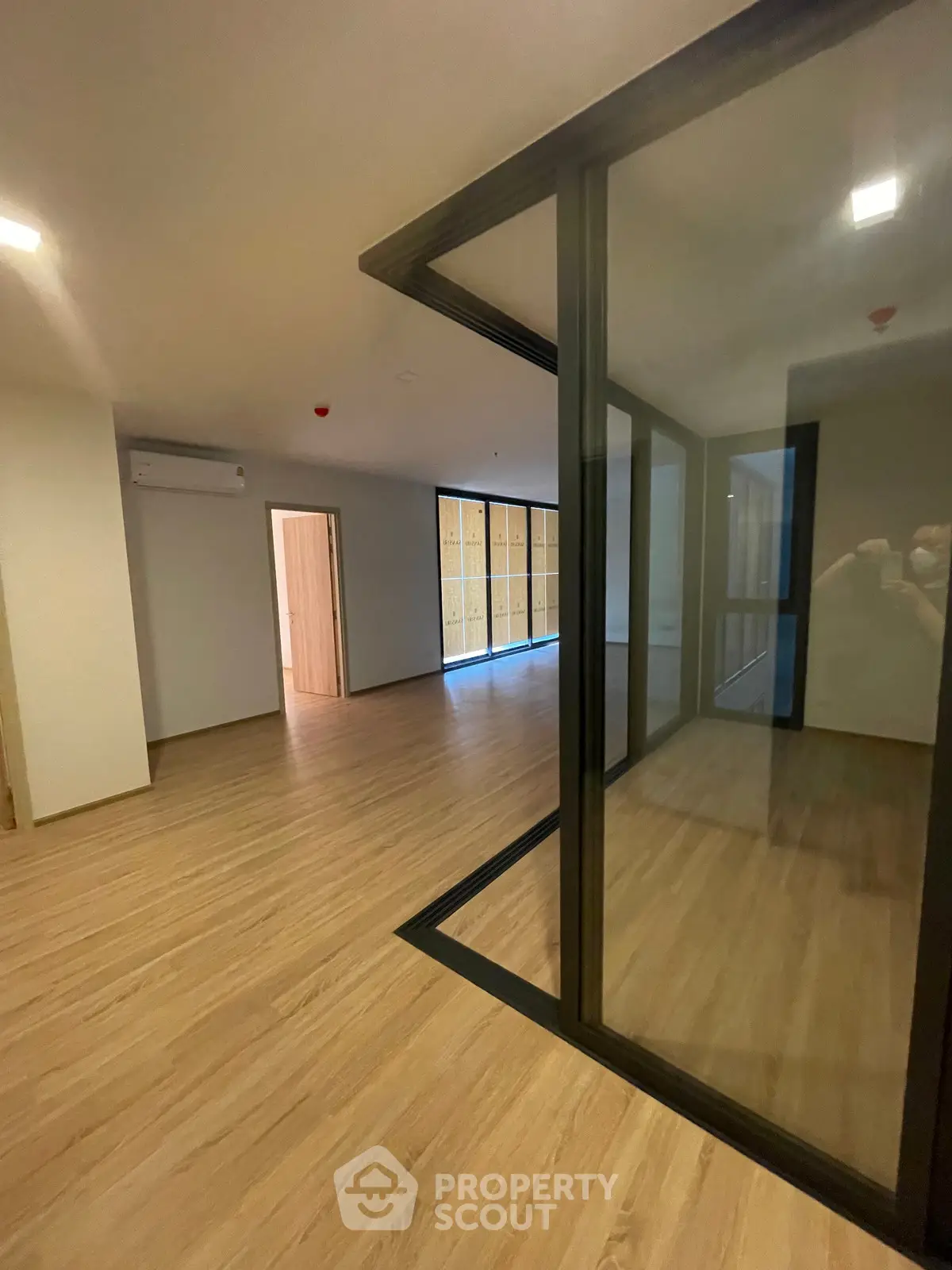 Spacious modern living room with wooden flooring and glass partition