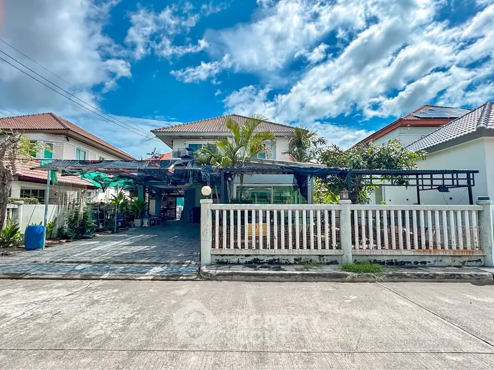 Charming suburban house with spacious driveway and lush greenery under a bright blue sky.