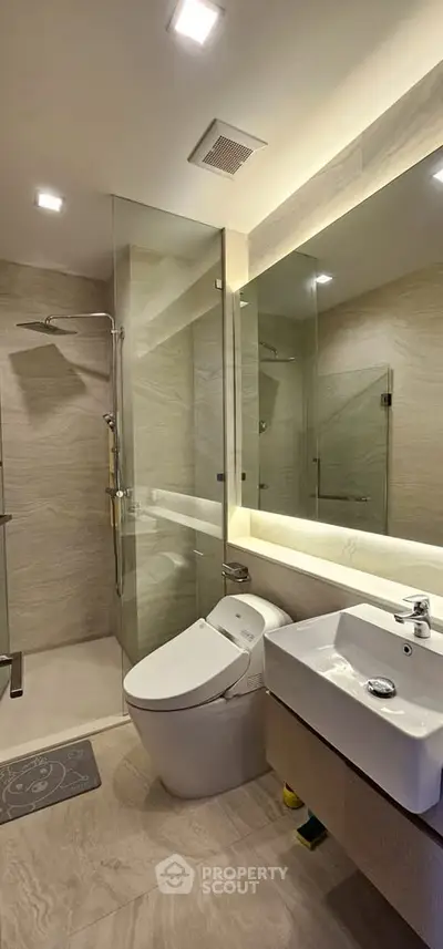 Modern bathroom with glass shower, sleek fixtures, and elegant lighting.