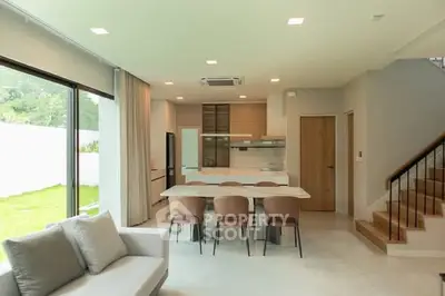 Spacious modern living room with open kitchen and garden view, perfect for family gatherings.