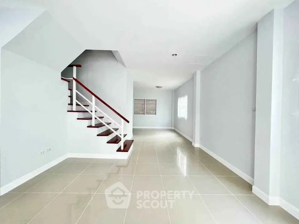 Spacious open-plan living area with modern staircase and tiled flooring