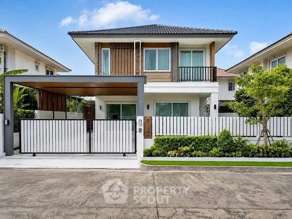 Modern two-story house with a sleek design, featuring a spacious driveway and lush landscaping.